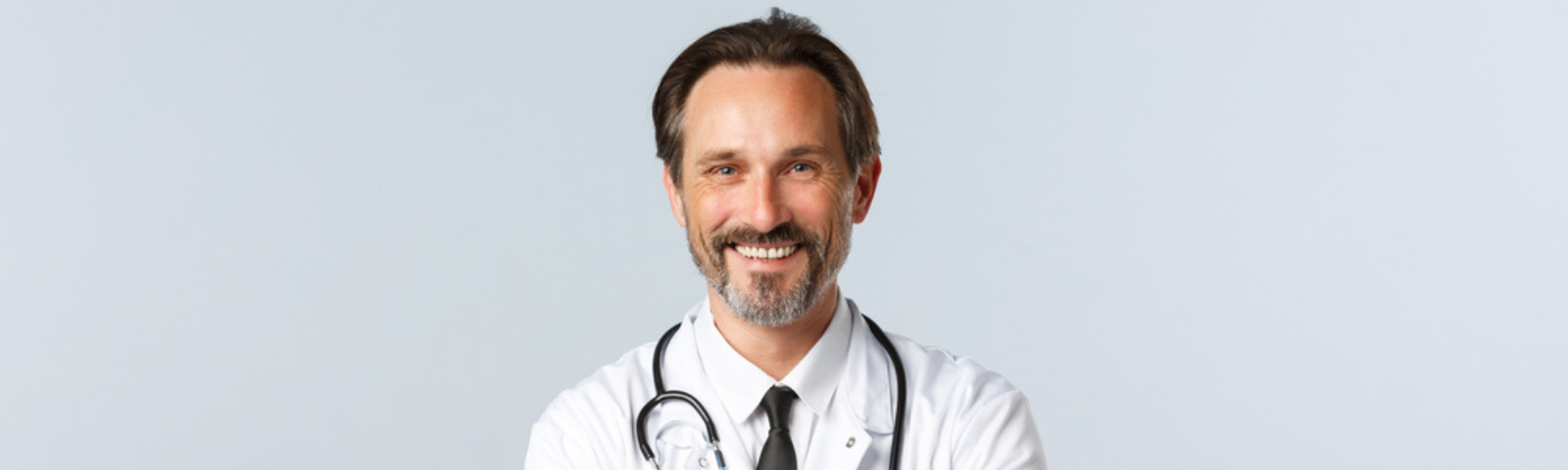 médico sonriente de brazos cruzado