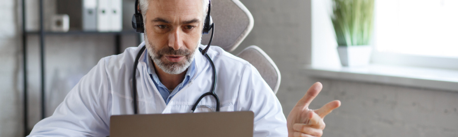 médico sentado frente a un computador realizando video consulta 
