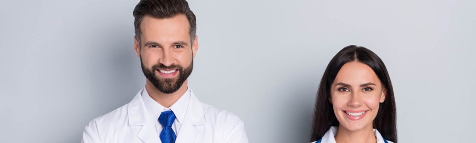 Un médico general fonasa hombre y una médico mujer mirando hacia la cámara felices