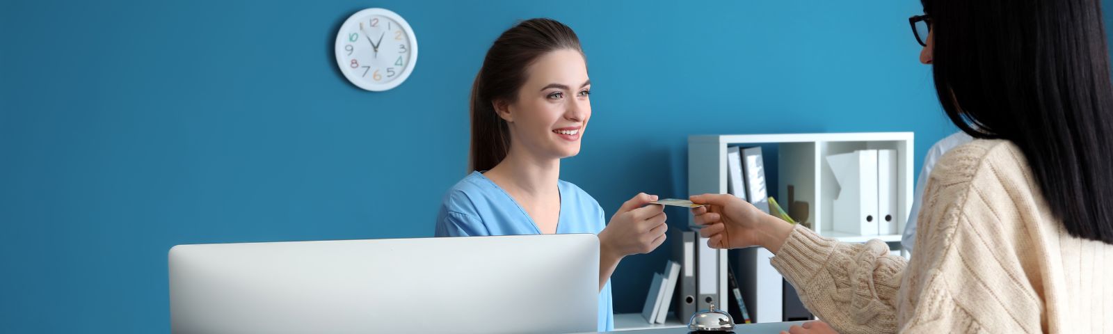paciente mujer pagando su bono médico a la secretaria de un centro médico
